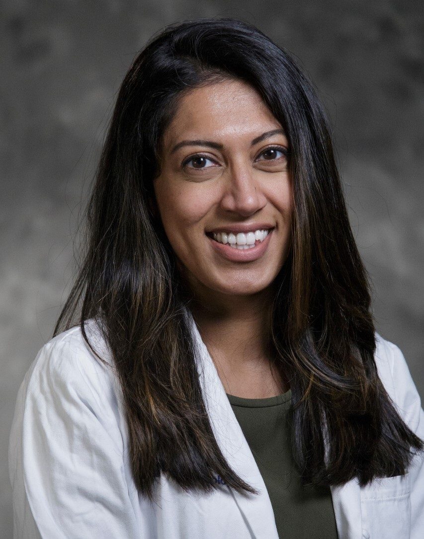 Woman in her mid-30s wearing a white lab coat, smiling