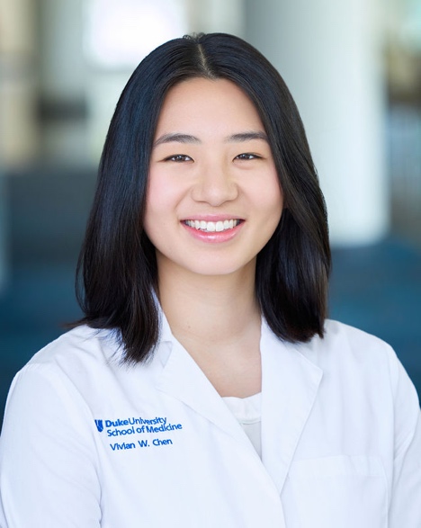 Woman in her mid-twenties wearing a white lab coat, smiling